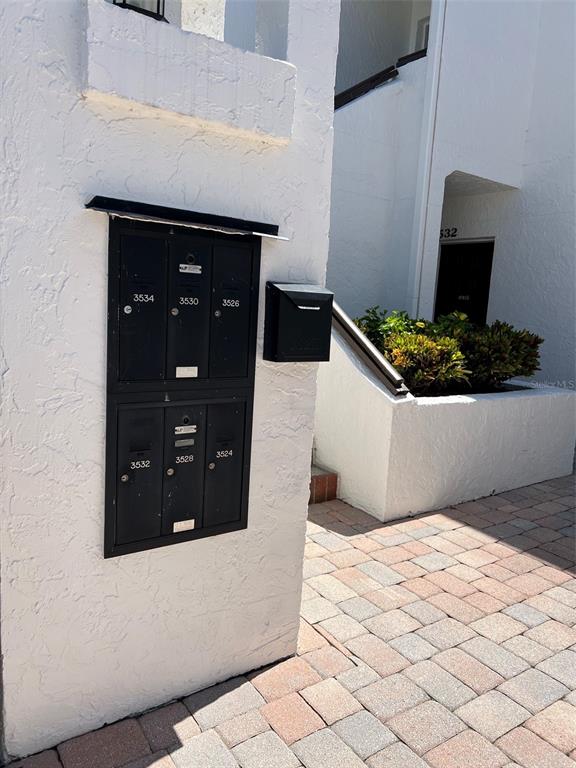 A wall-mounted cluster of black mailboxes sits on a white stucco exterior wall — 3534 RICHWOOD UNIT 44, SARASOTA, FL