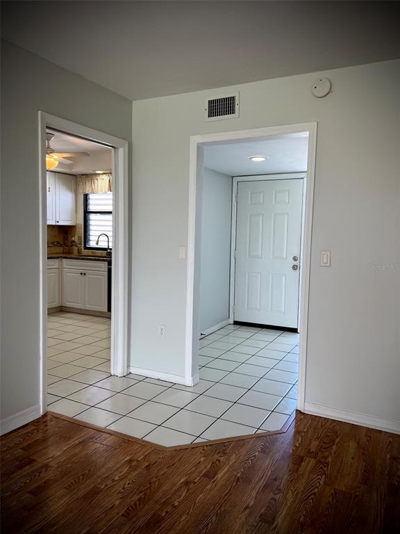 A view from a wood-floored room into a tiled kitchen and an entryway with a door — 3534 RICHWOOD UNIT 44, SARASOTA, FL
