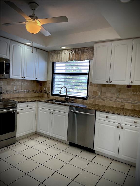 A kitchen features white cabinets, granite countertops, a stainless steel dishwasher, and tiled flooring — 3534 RICHWOOD UNIT 44, SARASOTA, FL