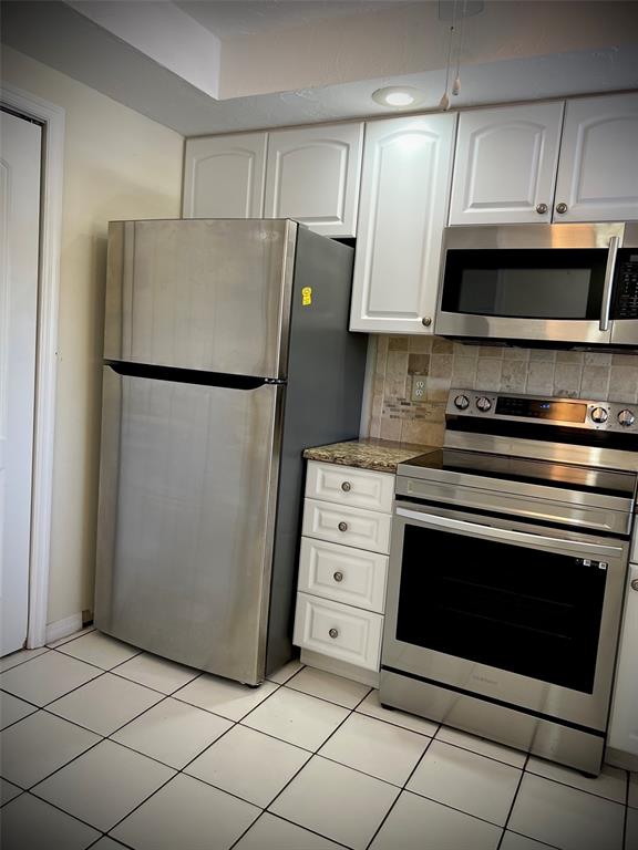A kitchen features stainless steel appliances, white cabinets, granite countertops, and white tile flooring — 3534 RICHWOOD UNIT 44, SARASOTA, FL