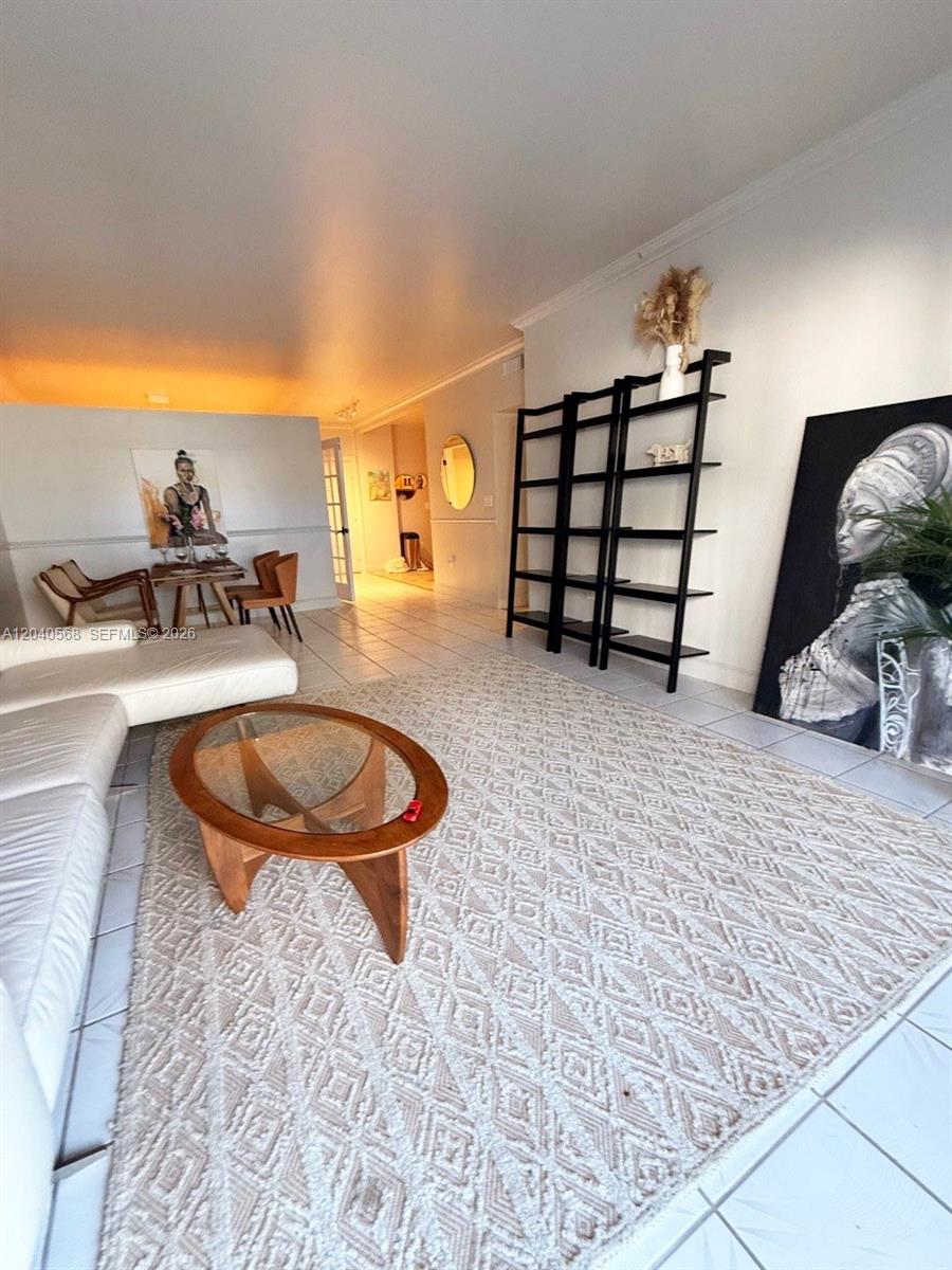 A living room features a white sofa, a glass coffee table, and a black bookshelf — 1701 S Ocean Dr # 105, Hollywood FL 33019, HOLLYWOOD, FL
