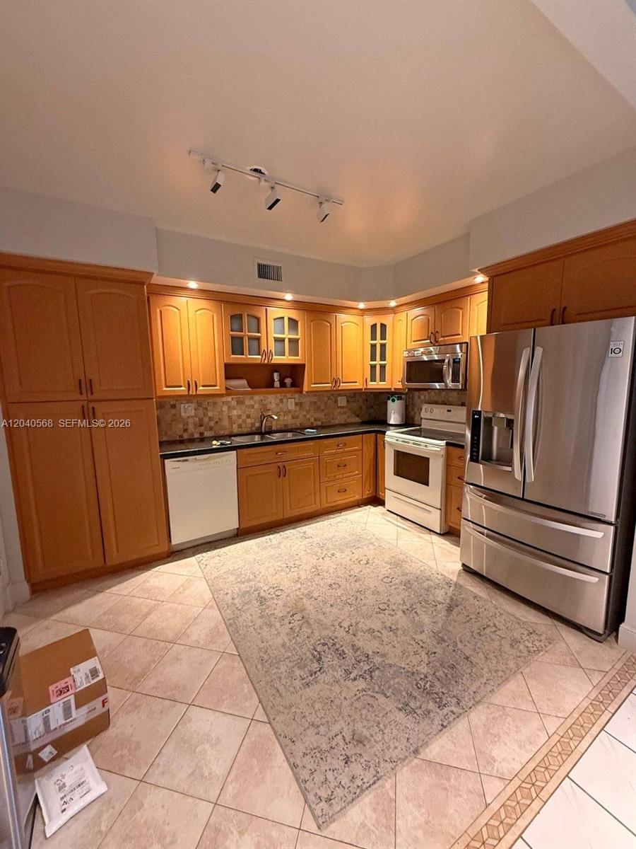 A kitchen features wood cabinets, stainless steel appliances, a tile floor, and a patterned rug — 1701 S Ocean Dr # 105, Hollywood FL 33019, HOLLYWOOD, FL