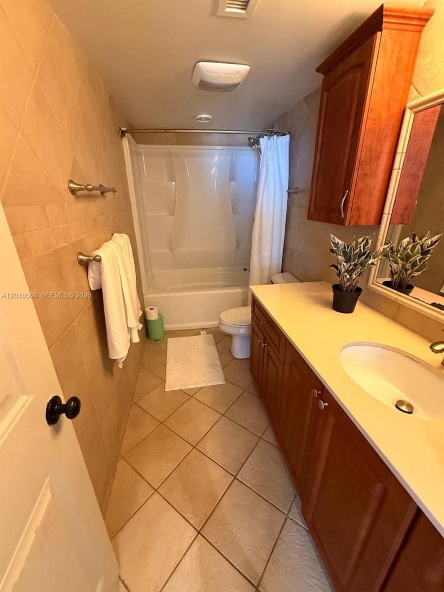 A bathroom features a tub-shower combination, a wooden vanity, and beige tiled flooring — 1701 S Ocean Dr # 105, Hollywood FL 33019, HOLLYWOOD, FL