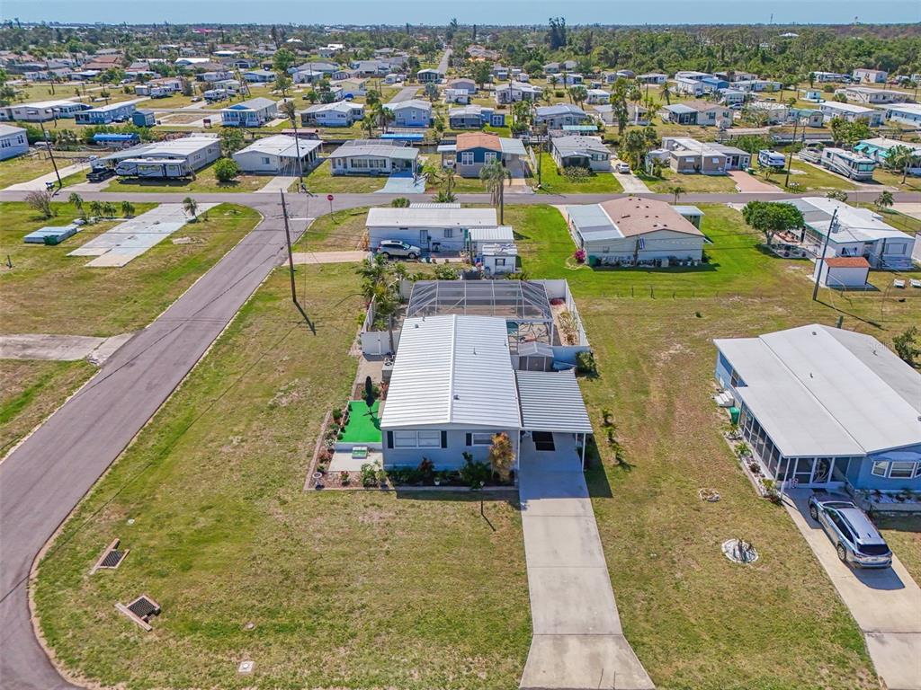 An aerial view shows a single-story house with a metal roof and screened-in pool area — 1376 FLAMINGO DRIVE, ENGLEWOOD, FL