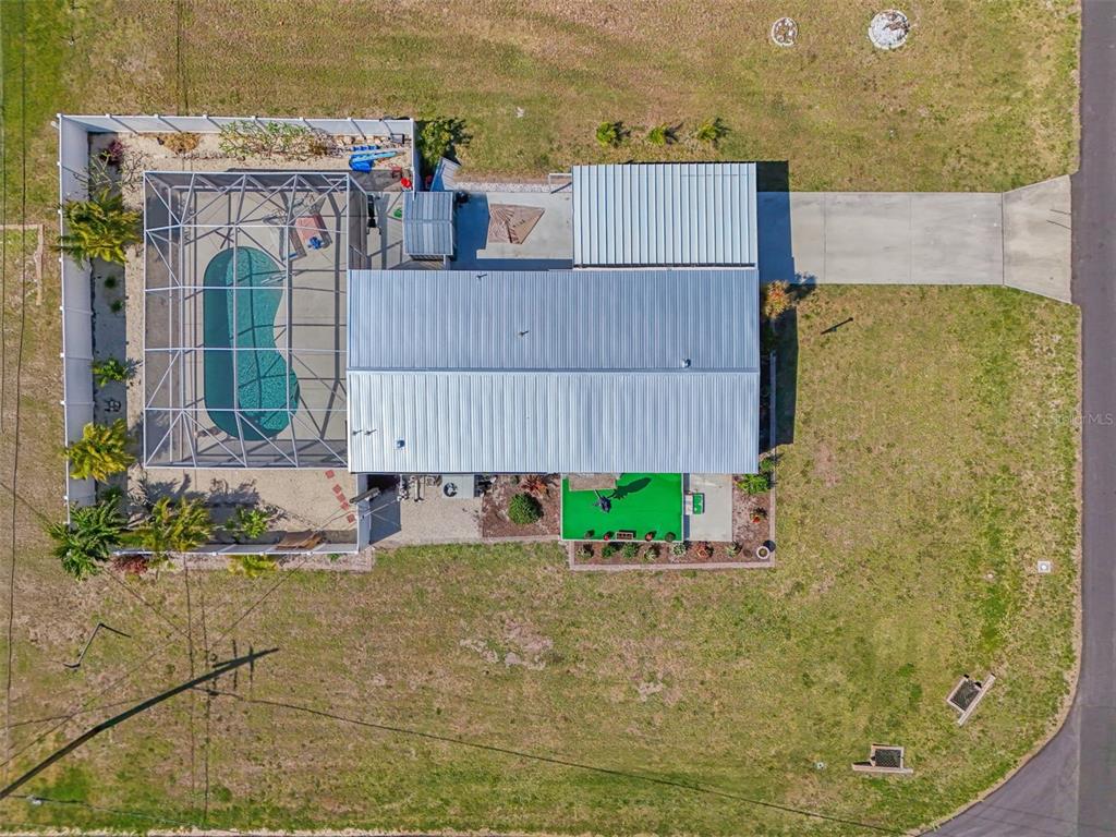 An aerial view shows a house with a metal roof, a screened pool, and a driveway — 1376 FLAMINGO DRIVE, ENGLEWOOD, FL
