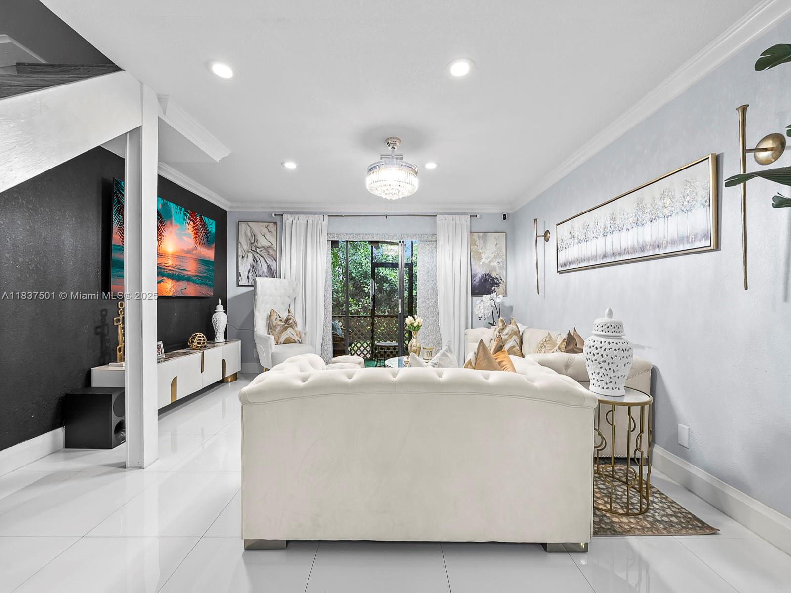 A modern living room features white tufted sofas, a black accent wall, and tile flooring — 10942 W Sample Rd # E1, Coral Springs FL 33065, CORAL SPRINGS, FL