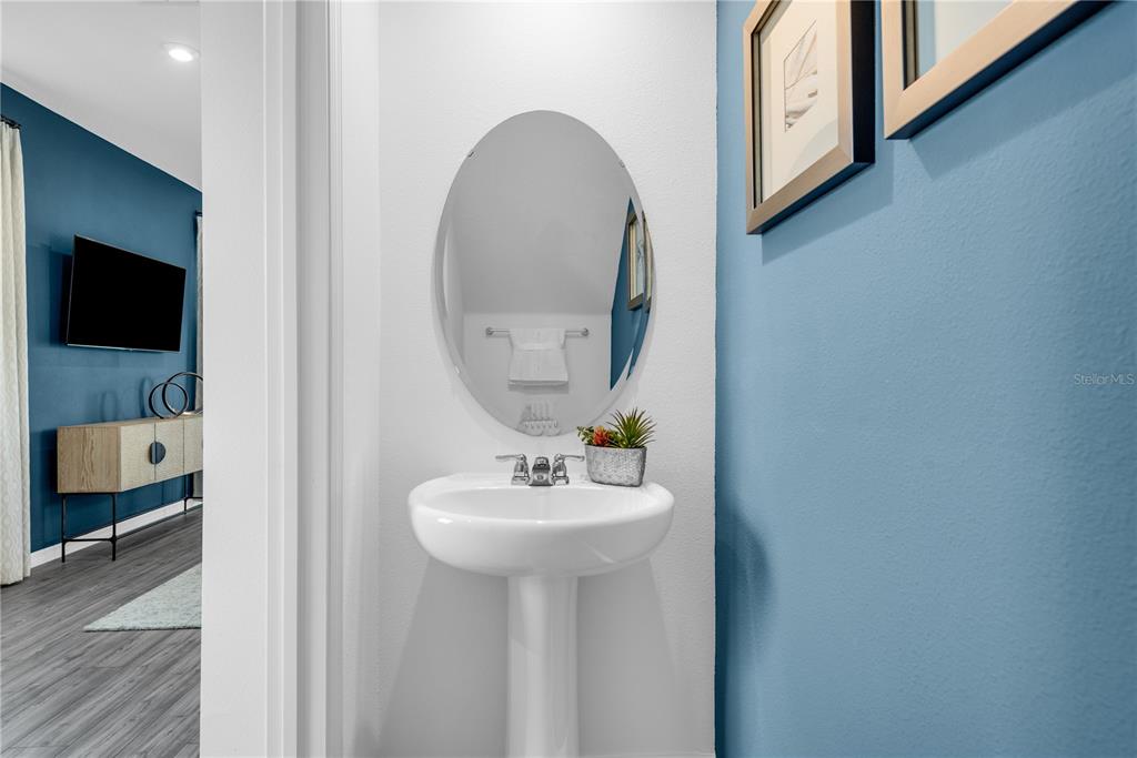 A powder room features a white pedestal sink, an oval mirror, and blue walls — 767 CASTLEFORD AVENUE, PALM BAY, FL