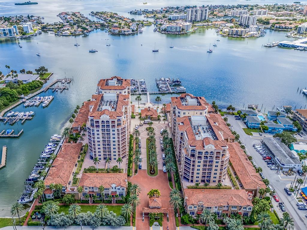 An aerial view shows two large residential buildings with red-tiled roofs beside a marina — 521 MANDALAY AVENUE UNIT 410, CLEARWATER BEACH, FL