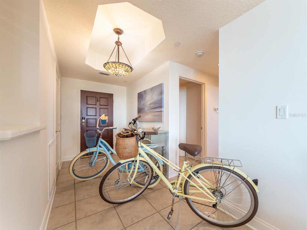 An entryway features tile flooring, a stained-glass pendant light, and two bicycles parked inside — 521 MANDALAY AVENUE UNIT 410, CLEARWATER BEACH, FL