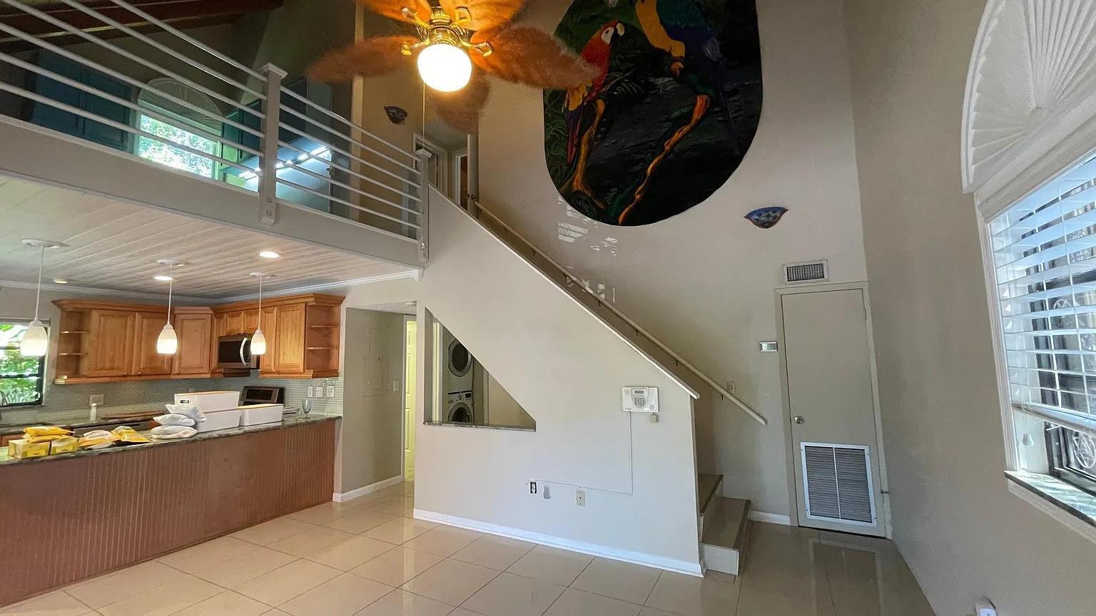 A living area with a kitchen, a staircase, a loft, and a large wall mural — 24 Bonita Avenue, Key Largo FL, KEY LARGO, FL