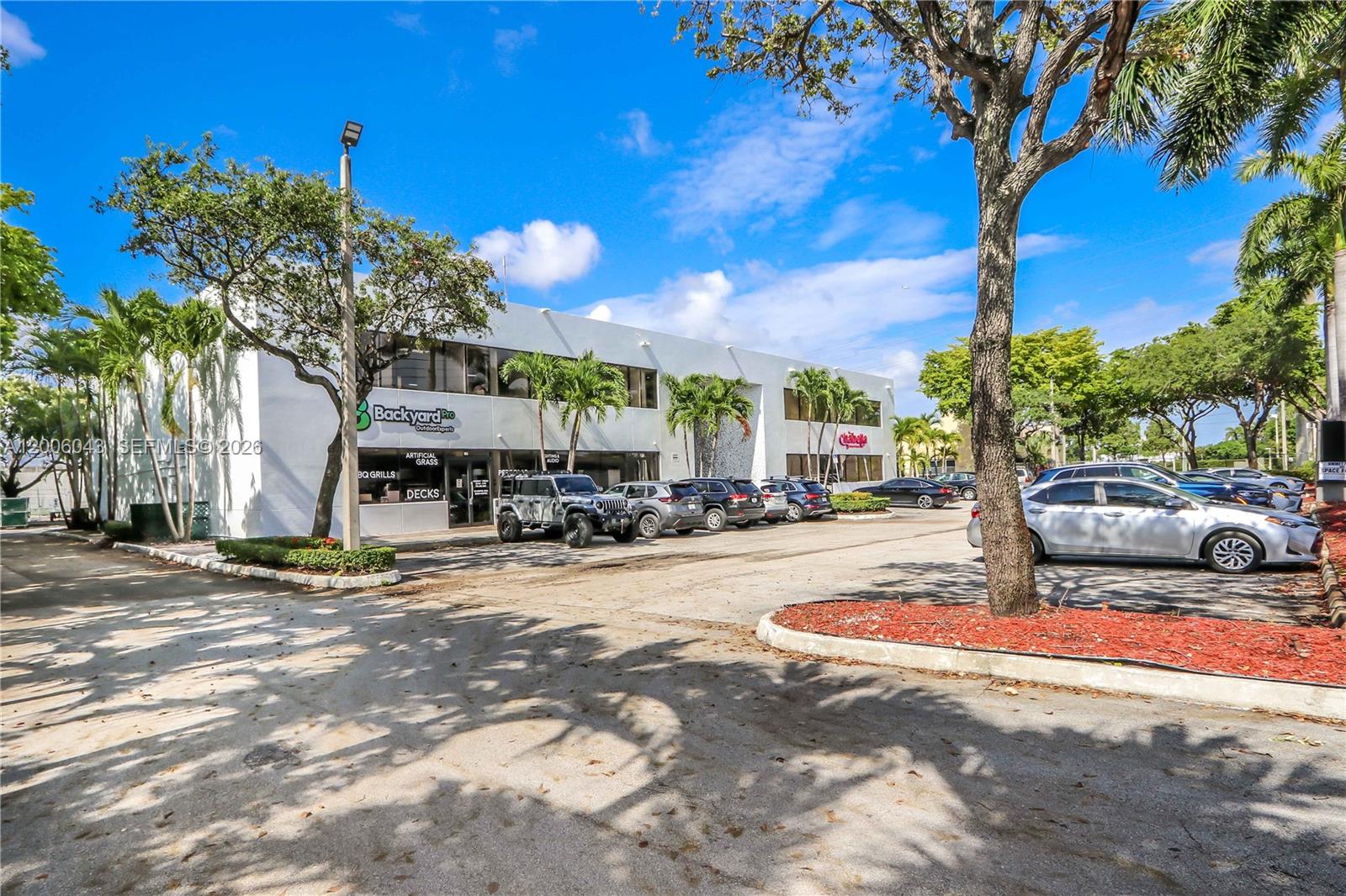 A two-story commercial building with a parking lot and palm trees in front — 7910 NW 25th St # 207, Doral FL 33122, DORAL, FL