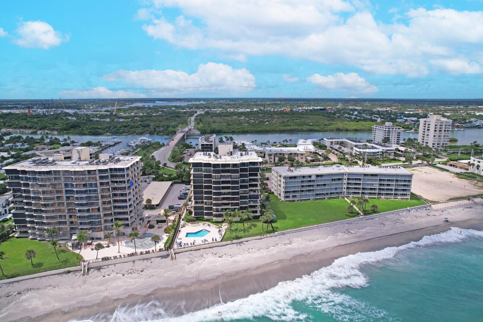 An aerial view of beachfront condominium buildings with pools and a nearby bridge — 200 S Beach Road # 802, Tequesta FL 33469, TEQUESTA, FL