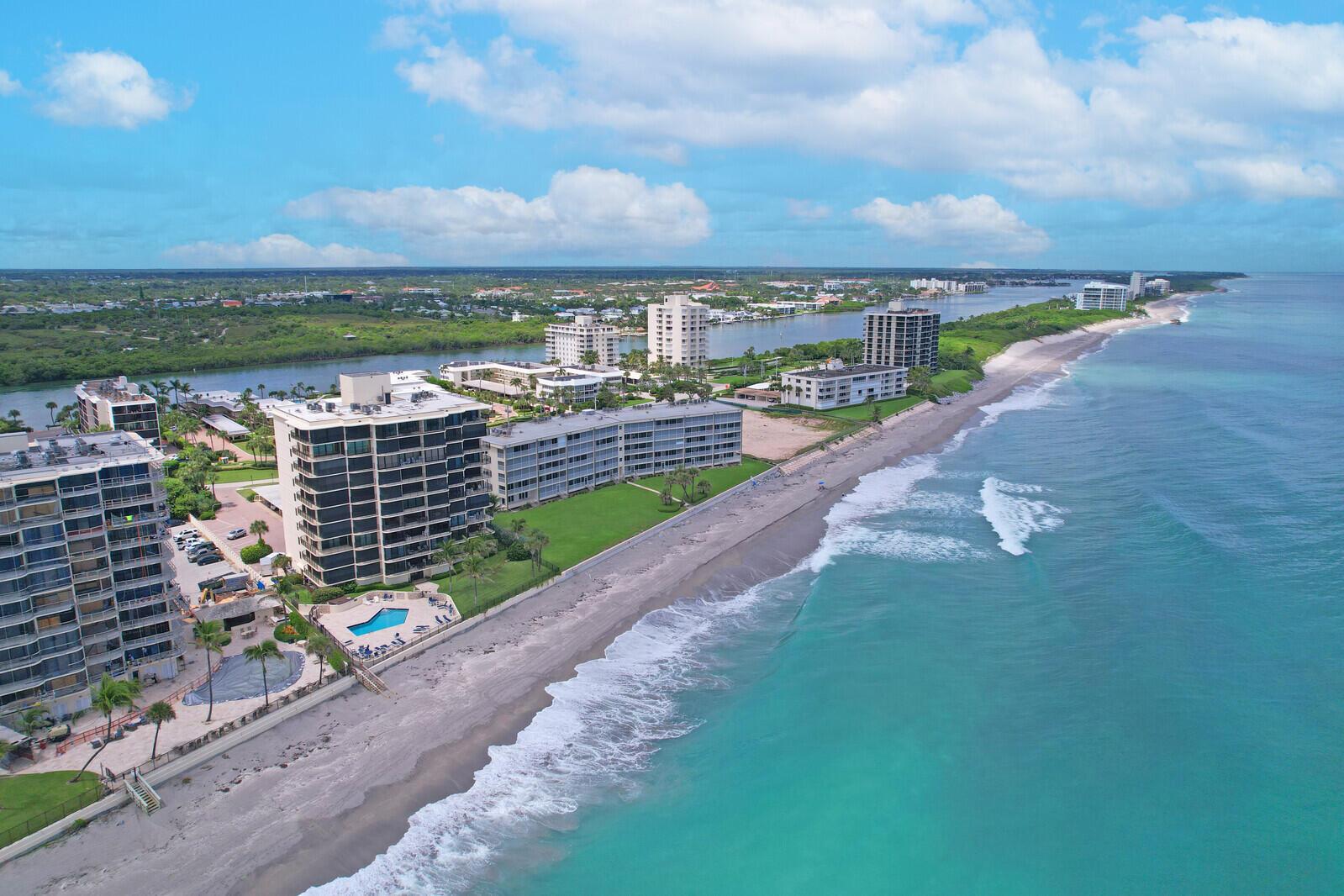 An aerial view shows beachfront high-rise condominiums along a coastline with a turquoise ocean — 200 S Beach Road # 802, Tequesta FL 33469, TEQUESTA, FL