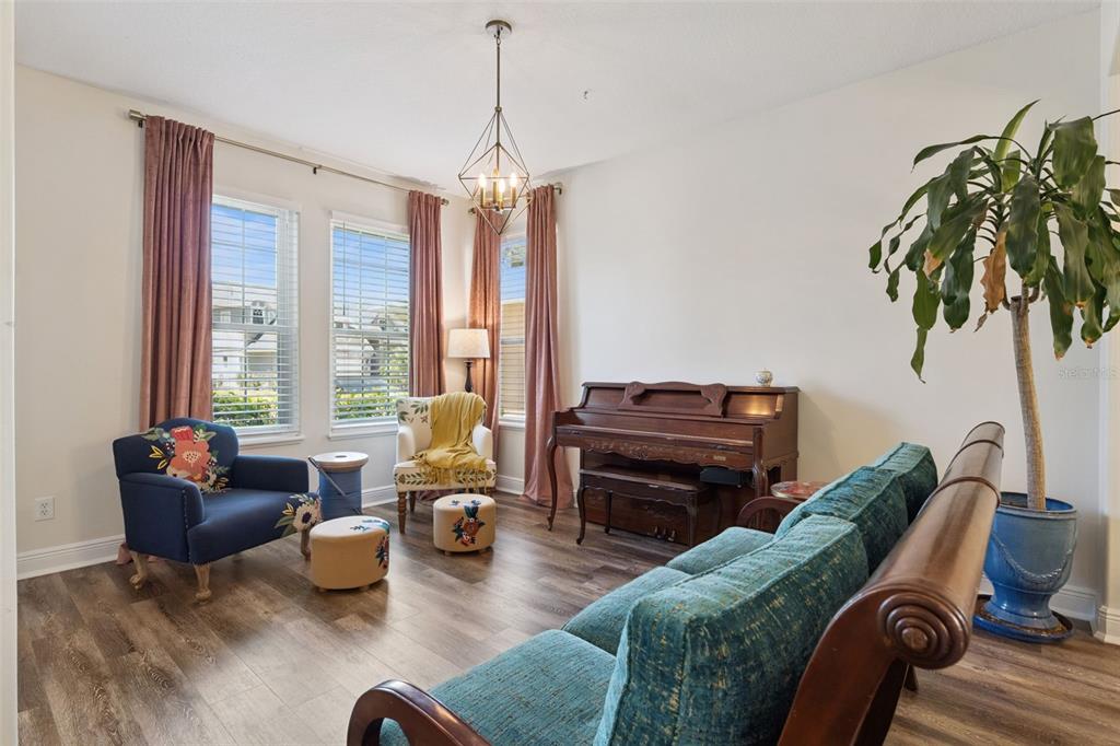A living room features a piano, a teal sofa, patterned armchairs, and wood-look flooring — 509 SPRING RIVER DRIVE, ORLANDO, FL