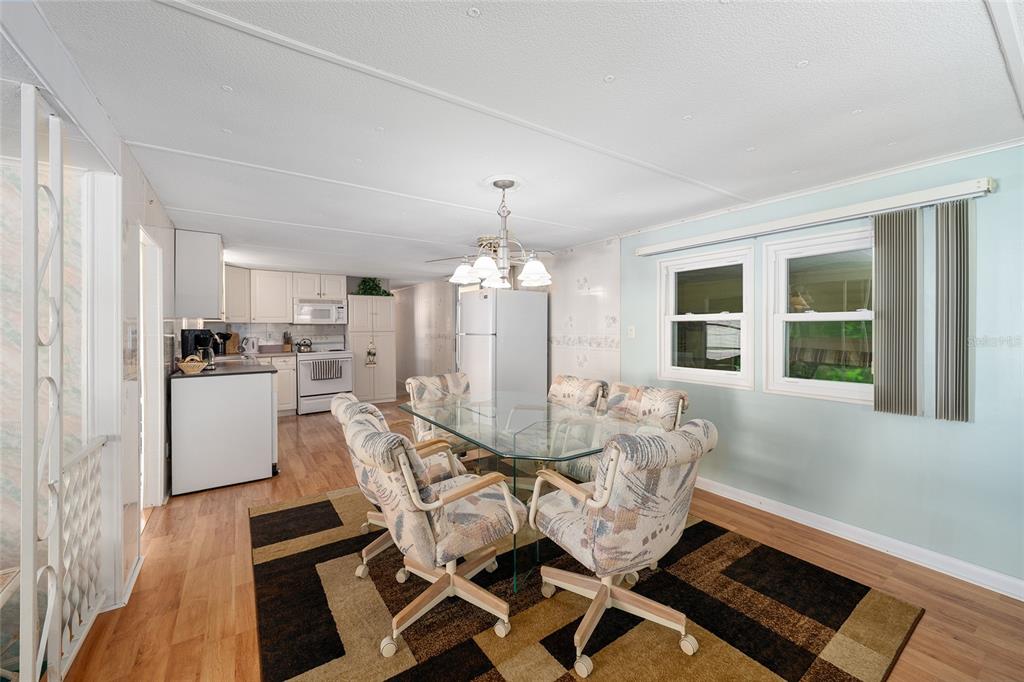 A dining area with a glass table and chairs sits adjacent to an open kitchen — 1027 VERMONT AVENUE, LADY LAKE, FL