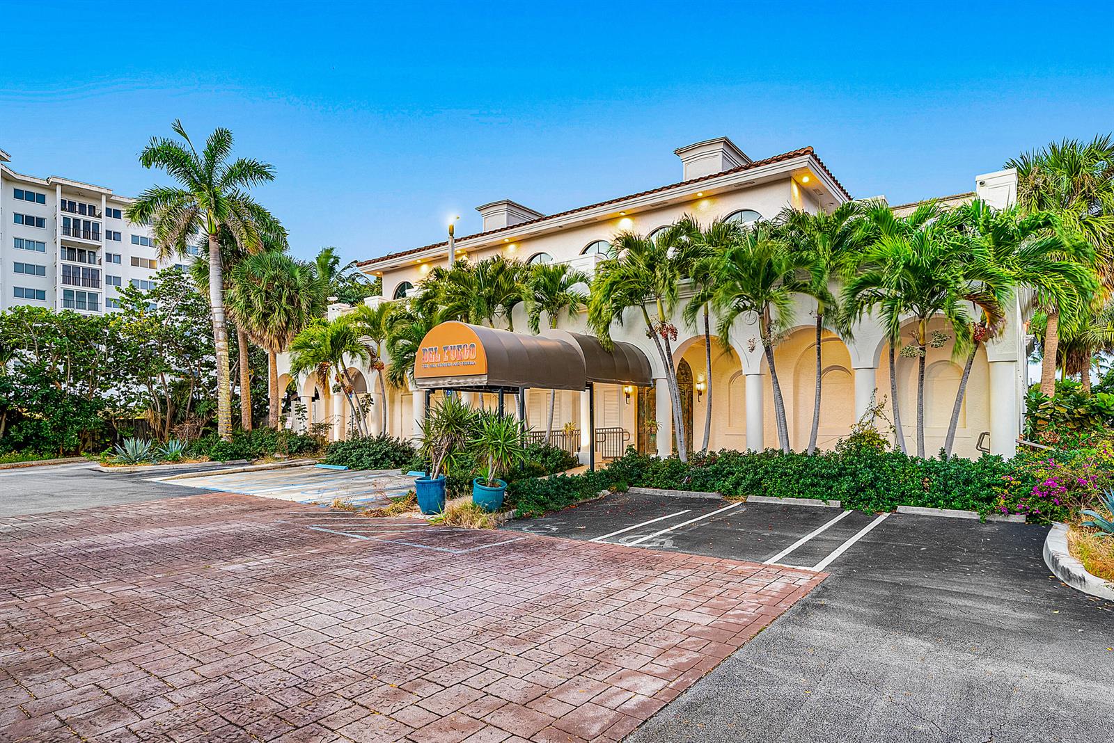 Exterior view of a two-story commercial building with a tan awning and palm trees — 900 E Atlantic Avenue # 22, Delray Beach FL 33483, DELRAY BEACH, FL
