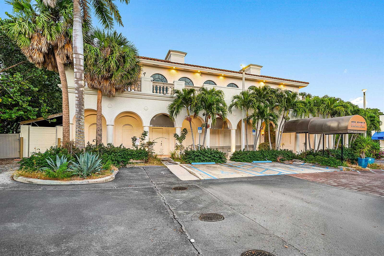 A two-story stucco building with arched entryways, palm trees, and a parking lot in front — 900 E Atlantic Avenue # 22, Delray Beach FL 33483, DELRAY BEACH, FL