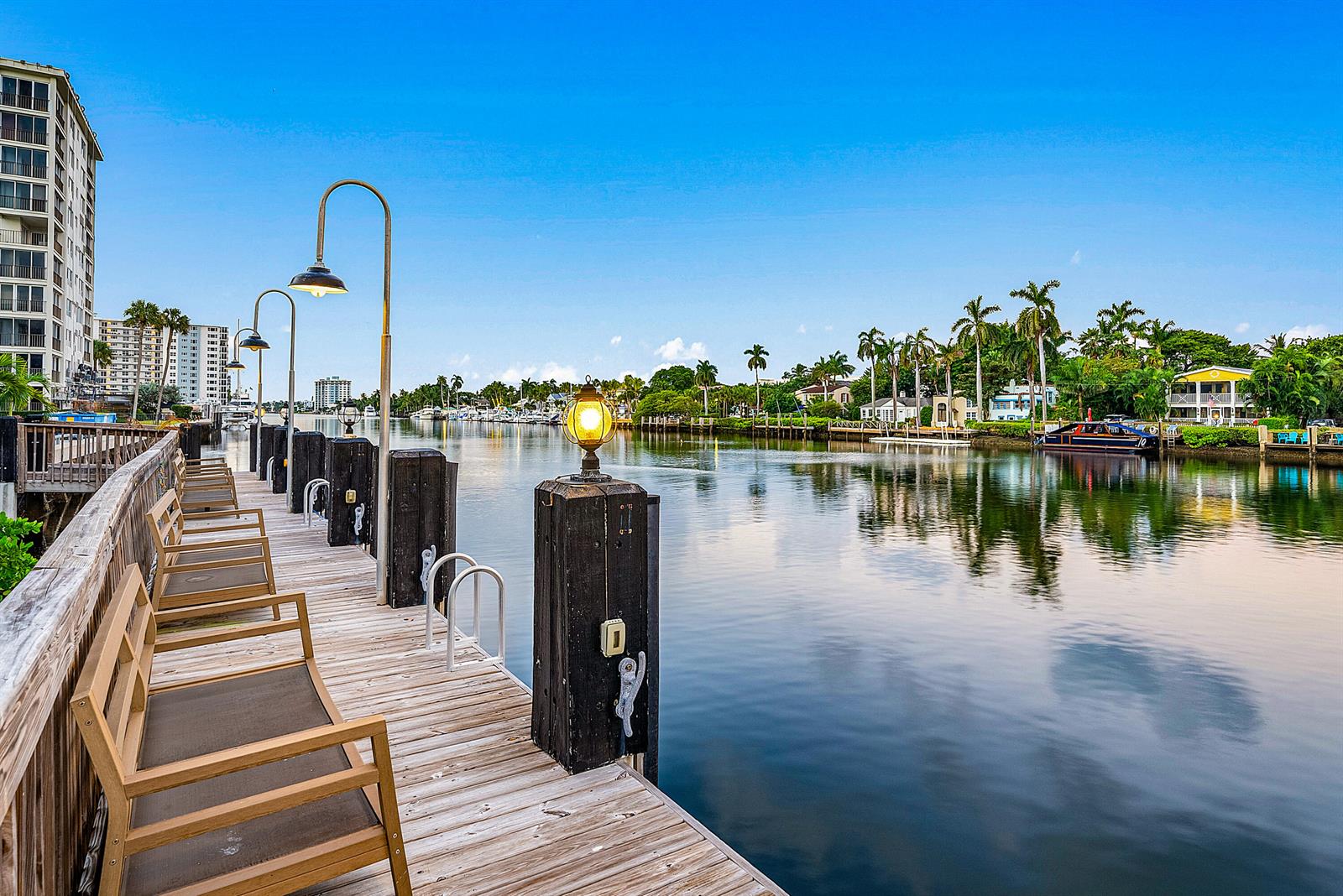 A wooden dock with chairs and lamp posts overlooks a calm canal lined with palm trees — 900 E Atlantic Avenue # 22, Delray Beach FL 33483, DELRAY BEACH, FL