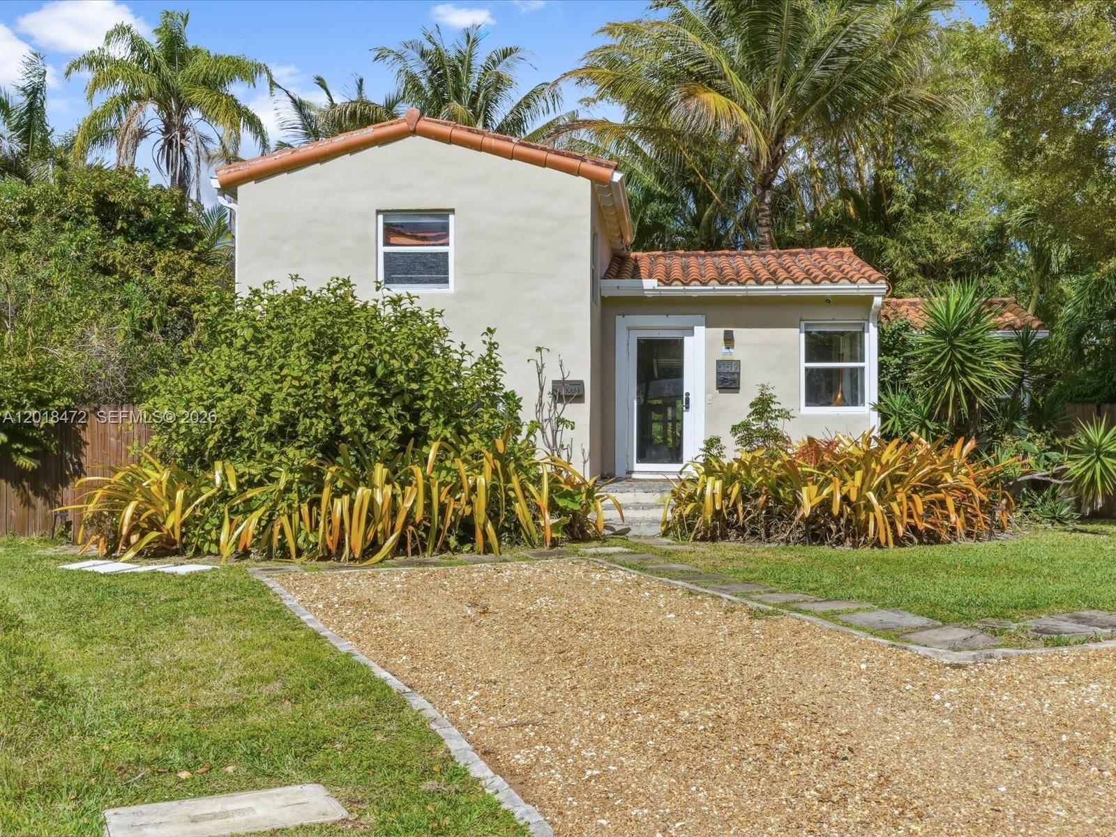 A two-story house with a gravel driveway, tiled roof, and lush landscaping in the front yard — 357 NE 117th St, Miami FL 33161, MIAMI, FL