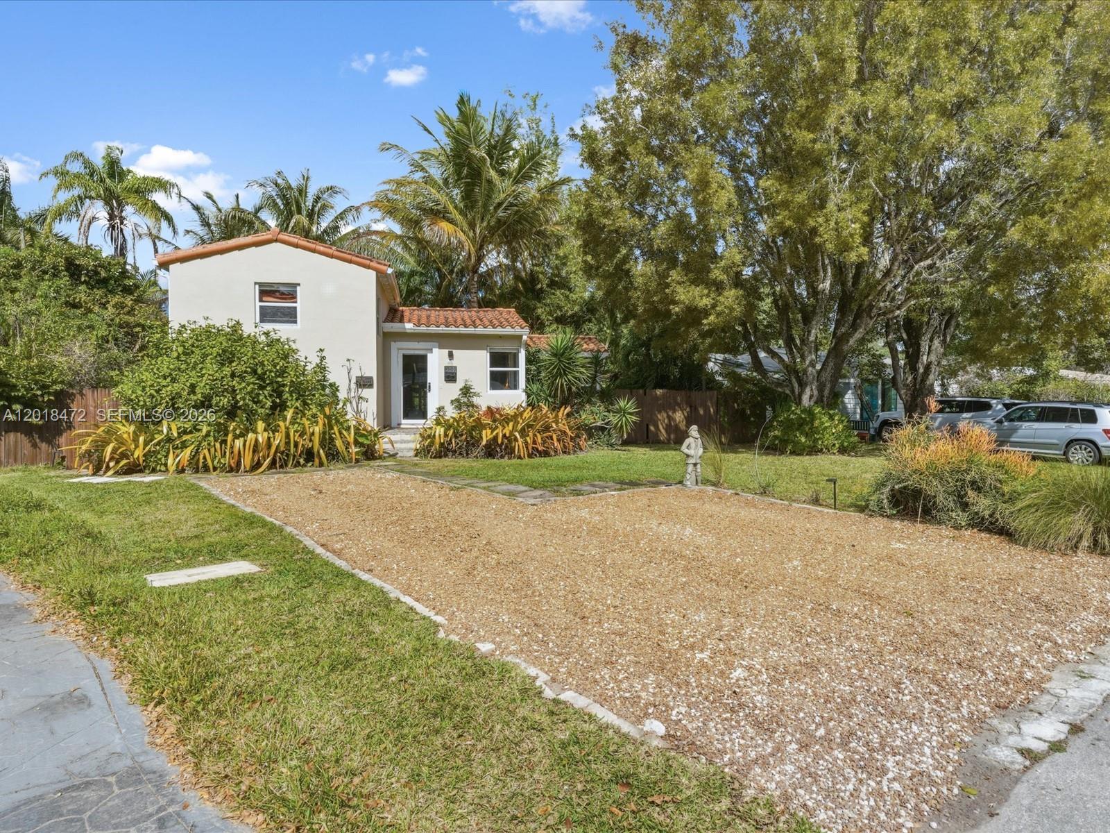 A two-story house with a gravel driveway, tile roof, and mature trees in the yard — 357 NE 117th St, Miami FL 33161, MIAMI, FL