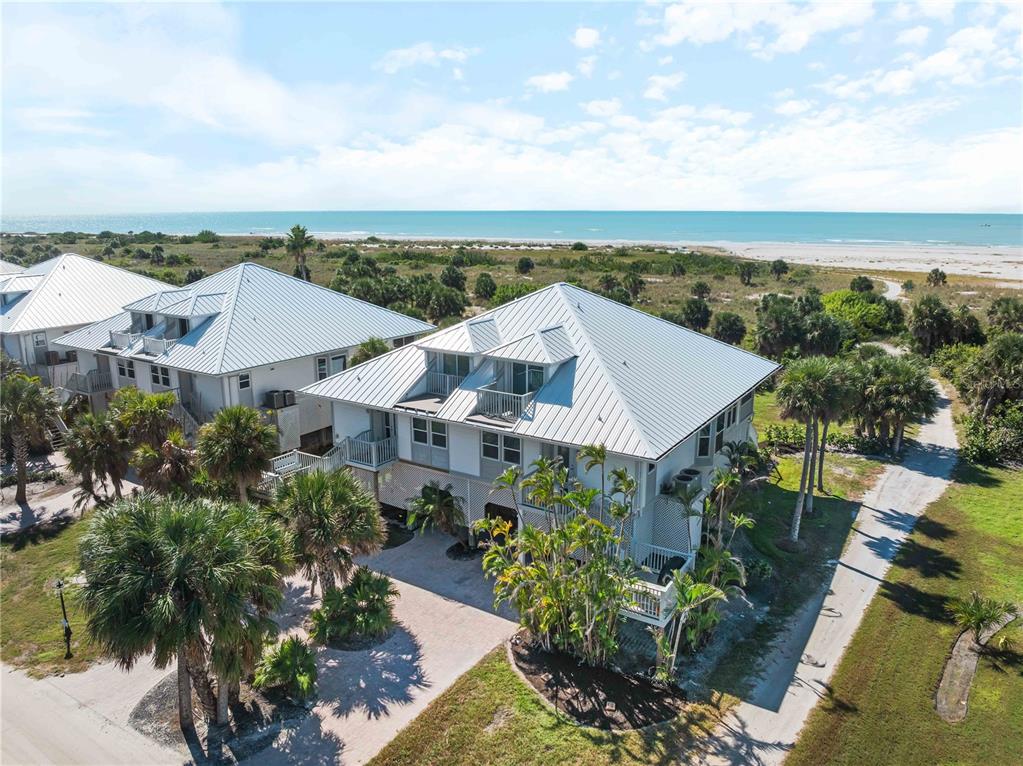 An aerial view shows two elevated coastal houses with metal roofs near a beach — 7104 PALM ISLAND DRIVE UNIT LE38, PLACIDA, FL