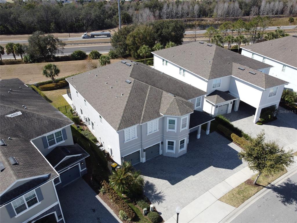 An aerial view shows the exterior of a two-story house with a paved driveway — 7666 FAIRFAX DRIVE, KISSIMMEE, FL