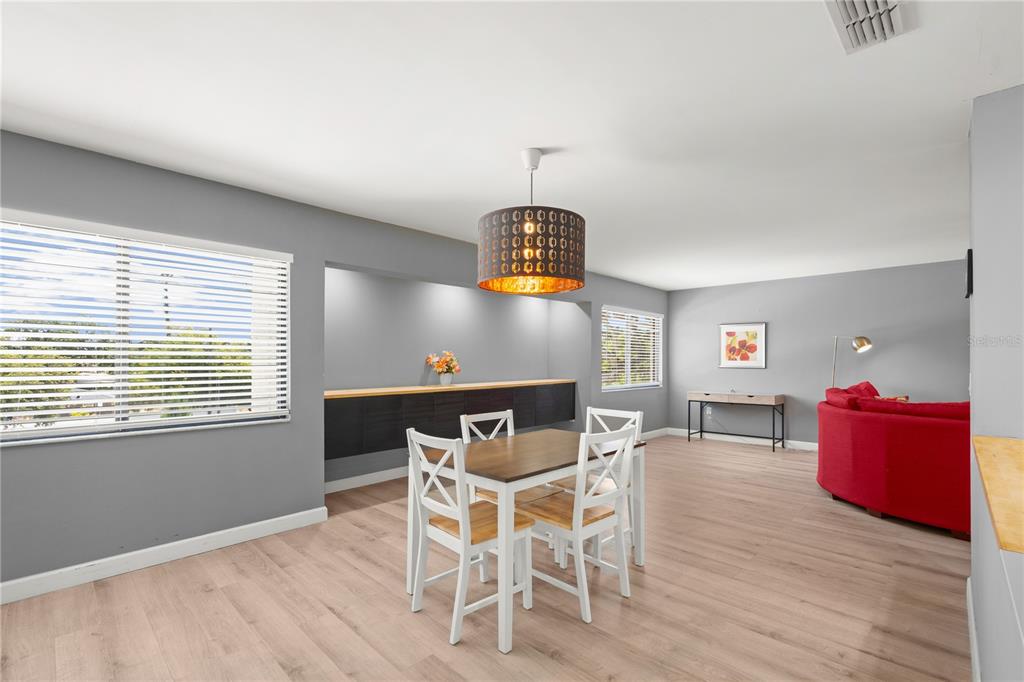 A dining area features a wooden table with white chairs, a pendant light, and gray walls — 2746 ORCHID OAKS DRIVE UNIT 301, SARASOTA, FL