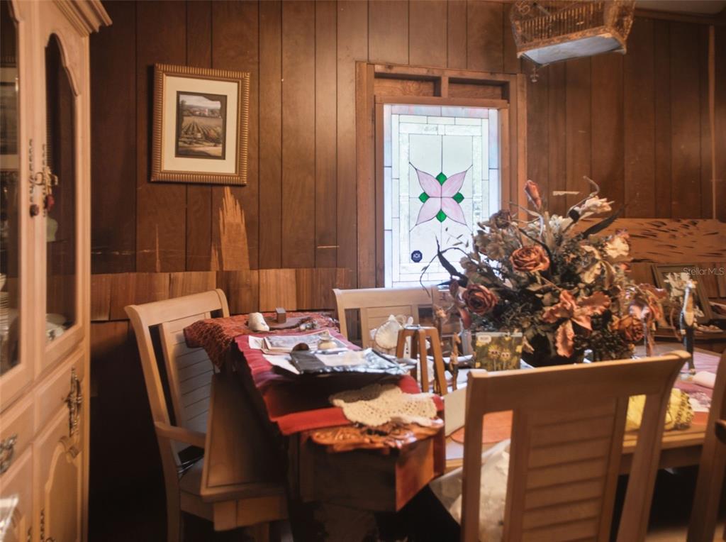 A dining room features wood-paneled walls, a stained-glass window, and a wooden table with chairs — 5229 SE 1ST STREET, TRENTON, FL