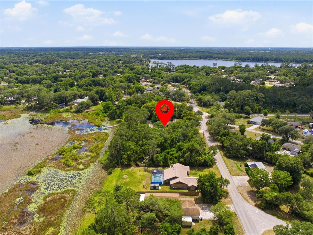 An aerial view shows a house with a pool near a lake and wooded area — W LAKE DRIVE, DELAND, FL