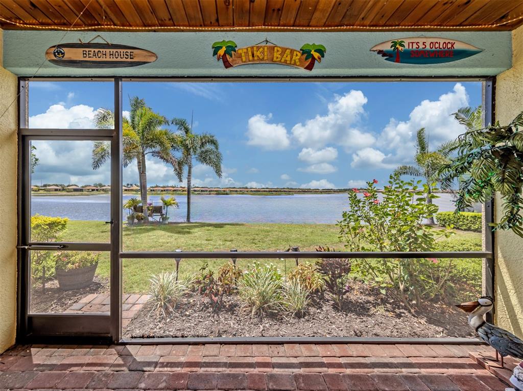 A screened-in patio overlooks a grassy lawn and a lake under a blue sky — 155 TOSCAVILLA BOULEVARD, NOKOMIS, FL