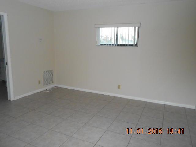 An empty room features light-colored walls, a single window with security bars, and tiled flooring — 23 Crossings Circle, Boynton Beach FL 33435, BOYNTON BEACH, FL