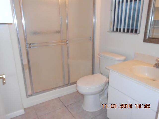A bathroom features a walk-in shower with sliding glass doors, a toilet, and a vanity — 23 Crossings Circle, Boynton Beach FL 33435, BOYNTON BEACH, FL
