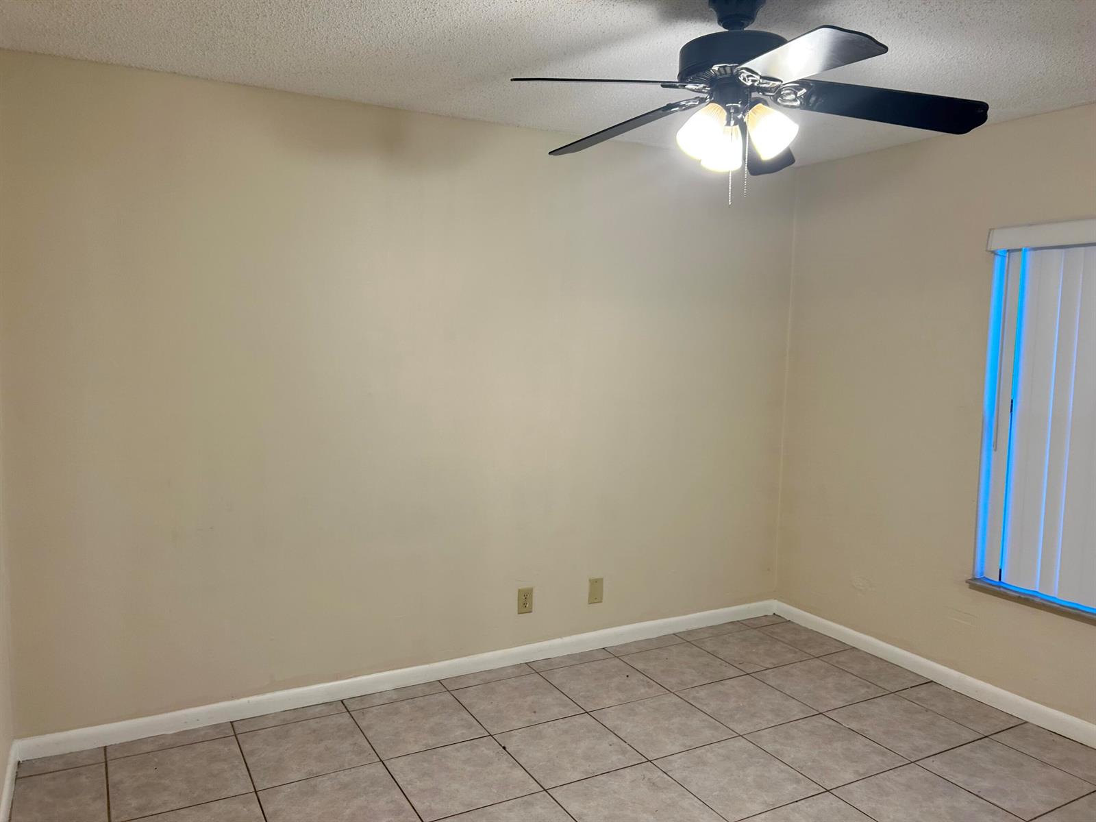 An empty room features beige walls, tile flooring, a ceiling fan, and a window — 23 Crossings Circle, Boynton Beach FL 33435, BOYNTON BEACH, FL