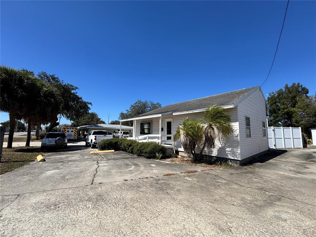 A light-colored, single-story house with a paved driveway and palm trees under a clear sky — 2924 KENILWORTH BOULEVARD, SEBRING, FL
