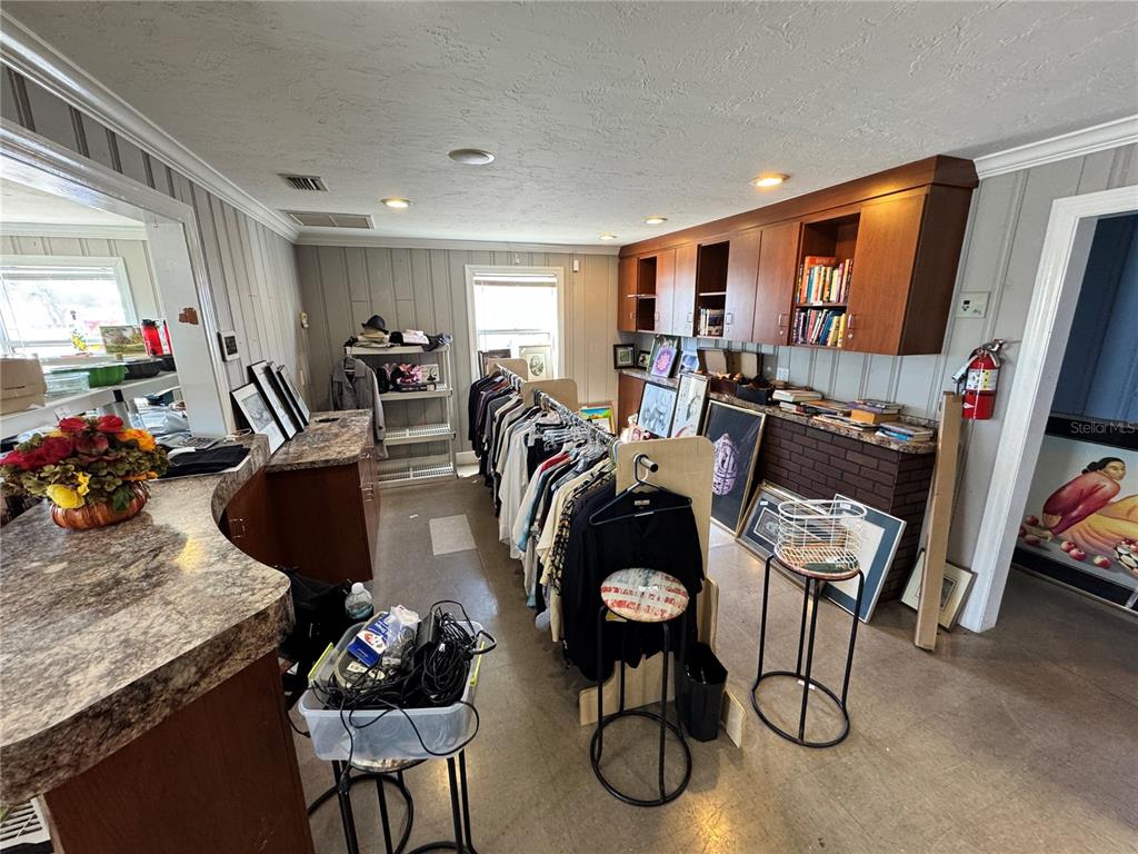 A room with wood-paneled walls, a clothing rack, built-in cabinets, and a brick accent wall — 2924 KENILWORTH BOULEVARD, SEBRING, FL