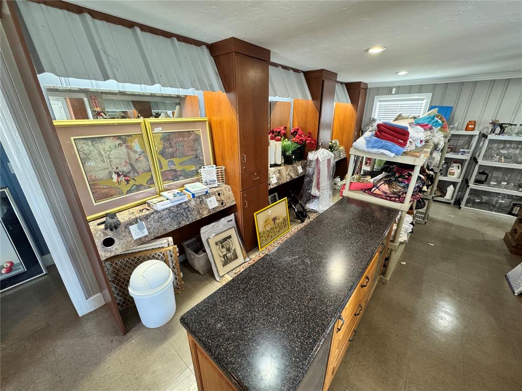 A room features a long dark countertop, wood cabinetry, and shelving units filled with various items — 2924 KENILWORTH BOULEVARD, SEBRING, FL