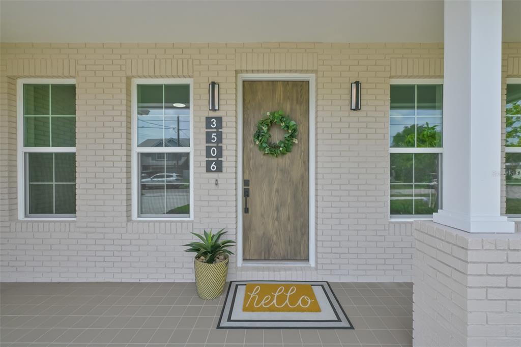 A front porch with a wood-look door, house numbers, a wreath, and a hello mat — 3506 W ROGERS AVENUE, TAMPA, FL