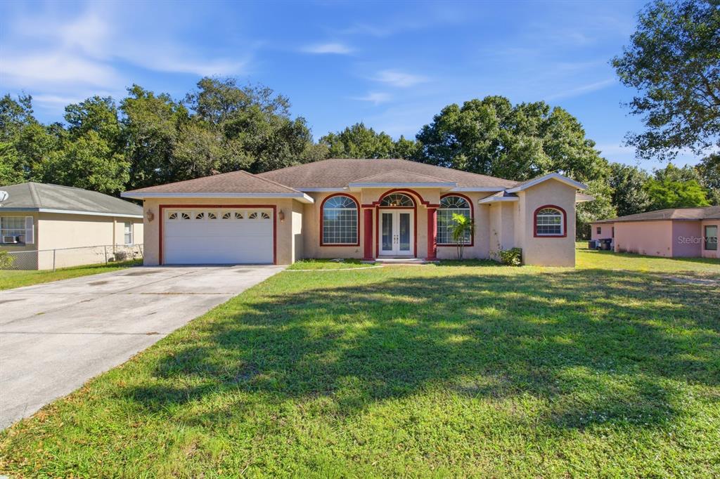 A single-story house with a two-car garage, arched windows, and a central double-door entrance — 1218 37TH STREET NW, WINTER HAVEN, FL