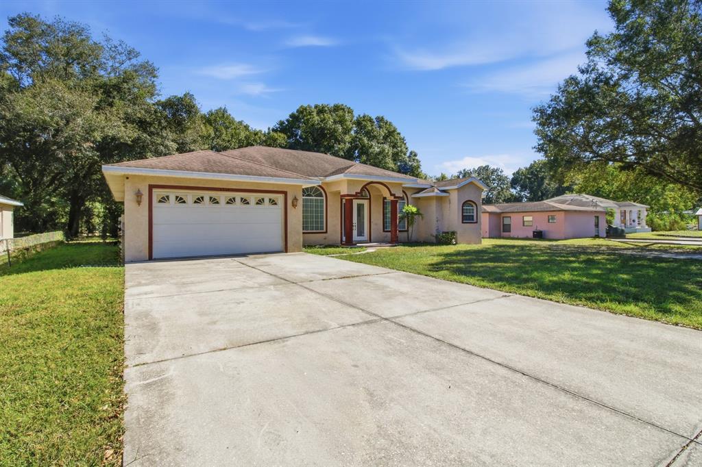 A single-story house with a two-car garage, a concrete driveway, and a tan exterior — 1218 37TH STREET NW, WINTER HAVEN, FL