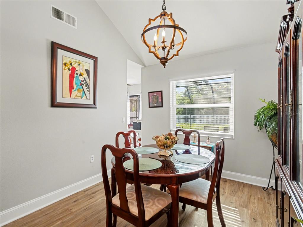 A dining room with a glass-topped table, wooden chairs, and a hanging orb chandelier — 5627 35TH COURT E, BRADENTON, FL