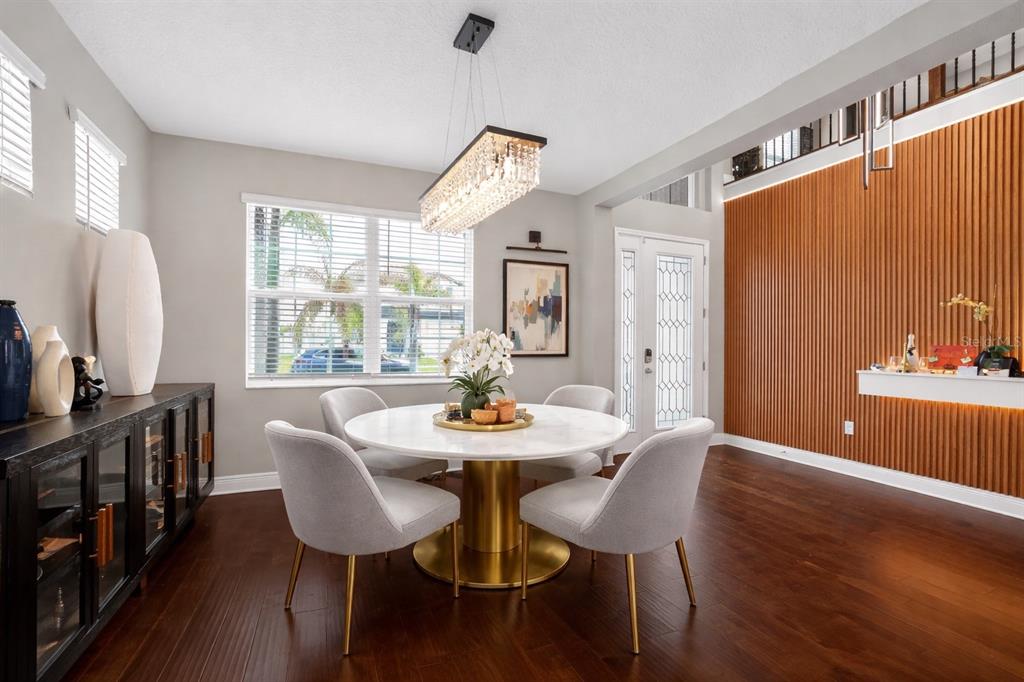 A dining room features a round marble table, four chairs, and a wood-slatted accent wall — 3103 MARINE GRASS DRIVE, WIMAUMA, FL