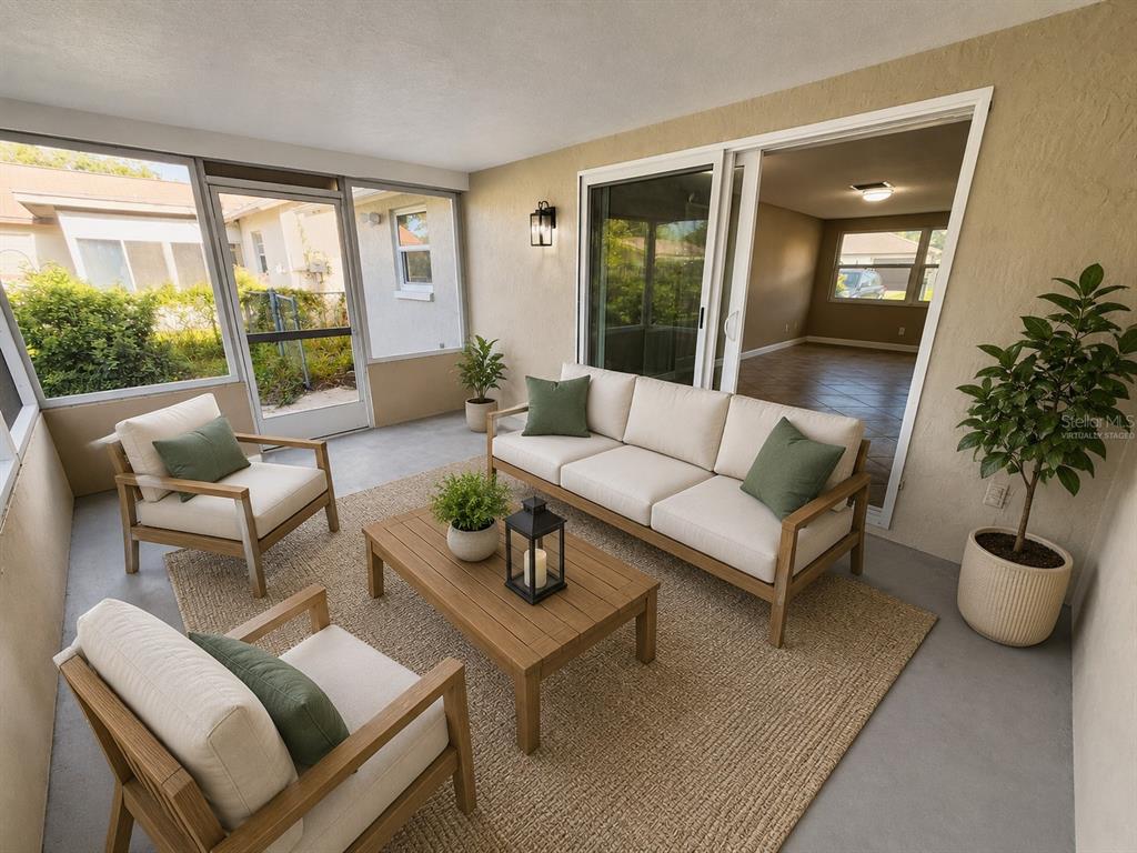 A sunroom features a sofa, two armchairs, a coffee table, and a sliding glass door — 7146 CARMEL AVENUE, NEW PORT RICHEY, FL
