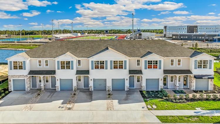 An aerial view of a multi-unit townhouse complex with gray garages and a shingled roof — 10707 TIGER LILY DRIVE, VENICE, FL