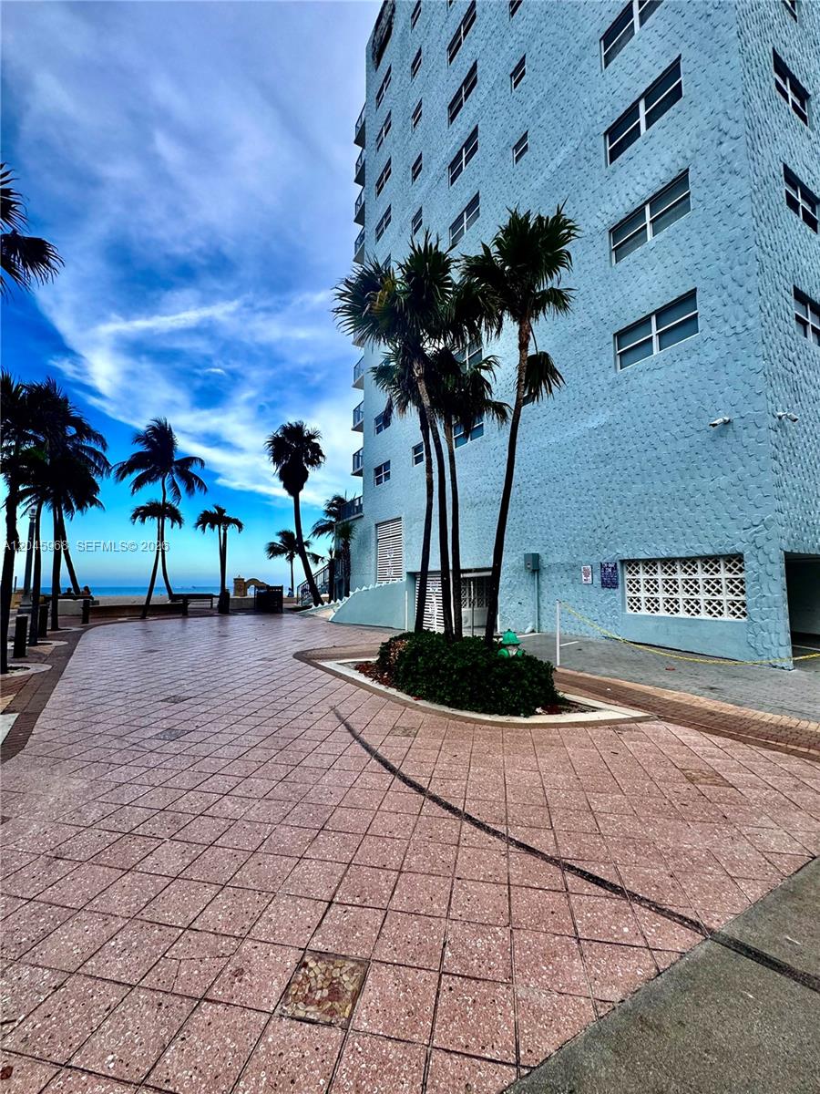 A light blue multi-story building stands beside a paved walkway with palm trees near the ocean — 400 N Surf Rd, Hollywood FL 33019, HOLLYWOOD, FL