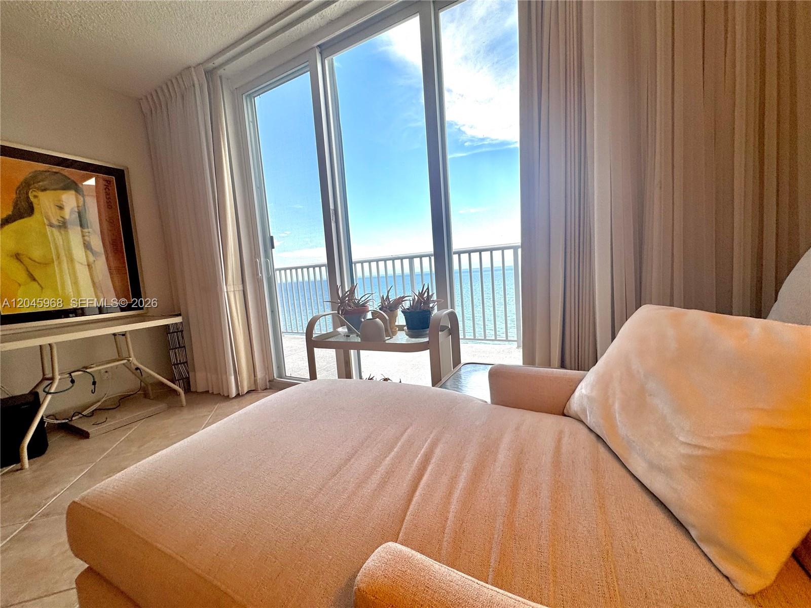 A living room features a chaise lounge, a framed print, and sliding doors overlooking the ocean — 400 N Surf Rd, Hollywood FL 33019, HOLLYWOOD, FL