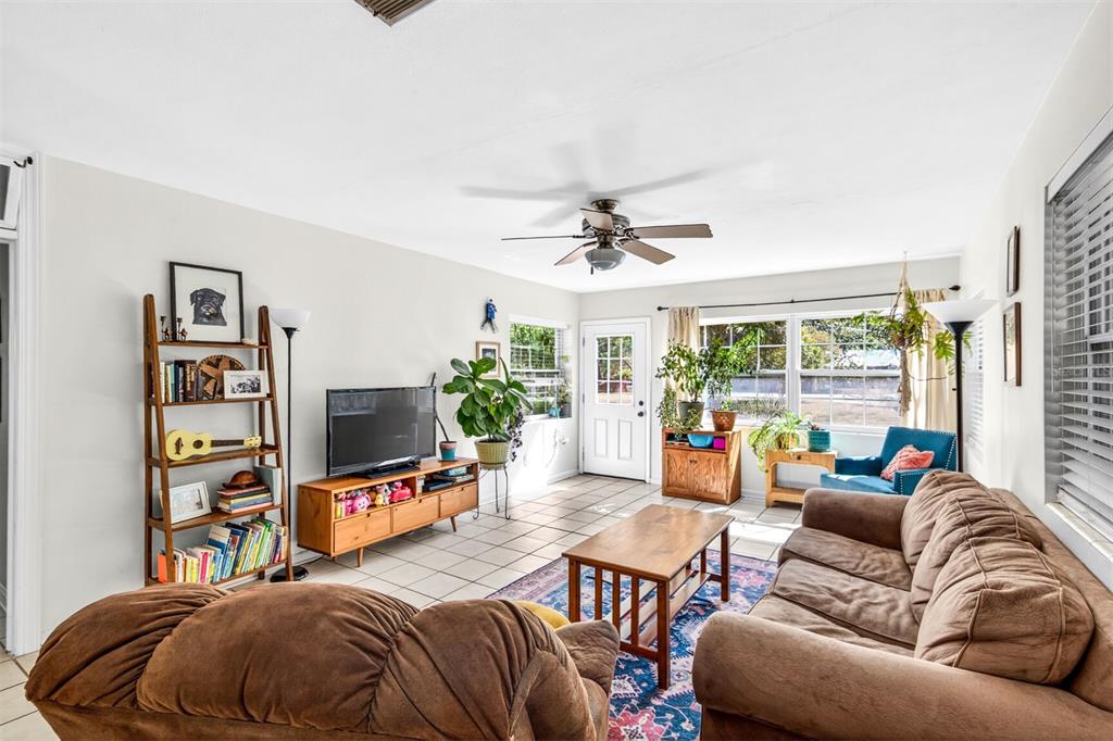 A living room features a brown sofa, a wooden coffee table, and a television console — 1006 NE 12TH AVENUE, GAINESVILLE, FL