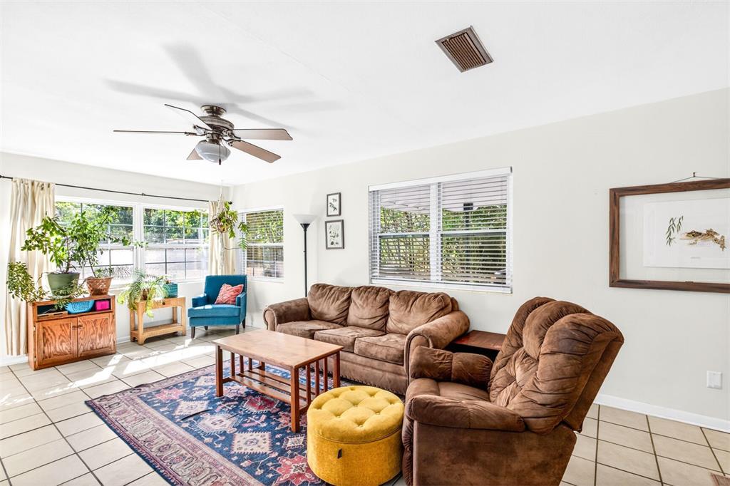 A living room with tile floors, a brown sofa, a recliner, and a patterned rug — 1006 NE 12TH AVENUE, GAINESVILLE, FL