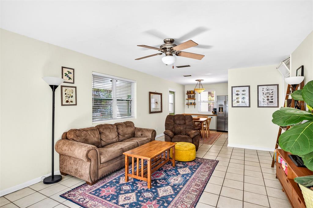 A living room with a brown sofa, armchair, coffee table, and tile flooring — 1006 NE 12TH AVENUE, GAINESVILLE, FL