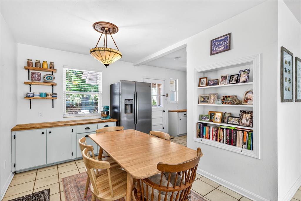 A dining room features a wooden table, built-in shelving, a stainless refrigerator, and tile flooring — 1006 NE 12TH AVENUE, GAINESVILLE, FL