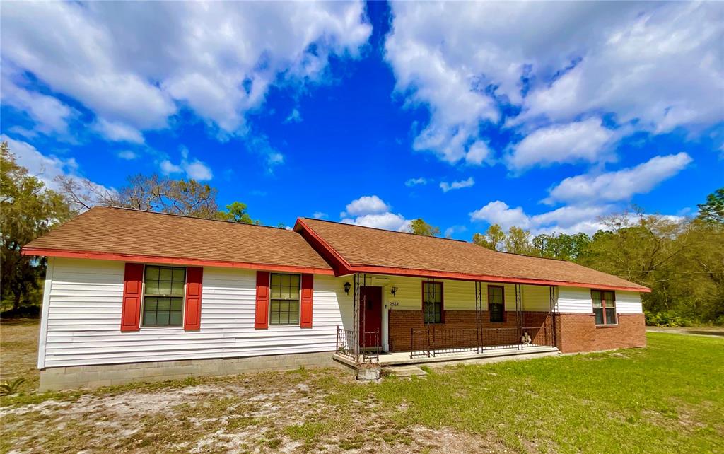 A single-story house with white siding, brick accents, red shutters, and a covered front porch — 2569 SE 50TH STREET, KEYSTONE HEIGHTS, FL